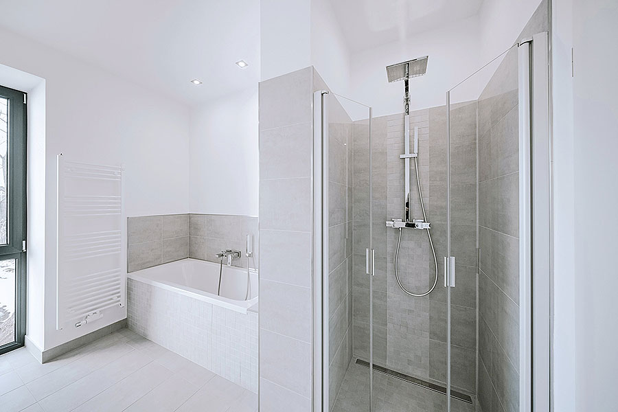Helles Bad mit bodengleicher Dusche, Badewanne, Handtuchheizkörper und großem Fenster in moderner Fliesengestaltung