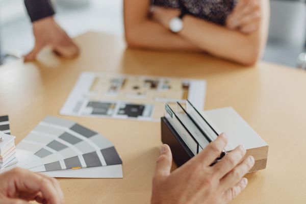 Beratungsgespräch mit Farbmustern und Materialproben für Innenarchitektur oder Bauplanung am Tisch