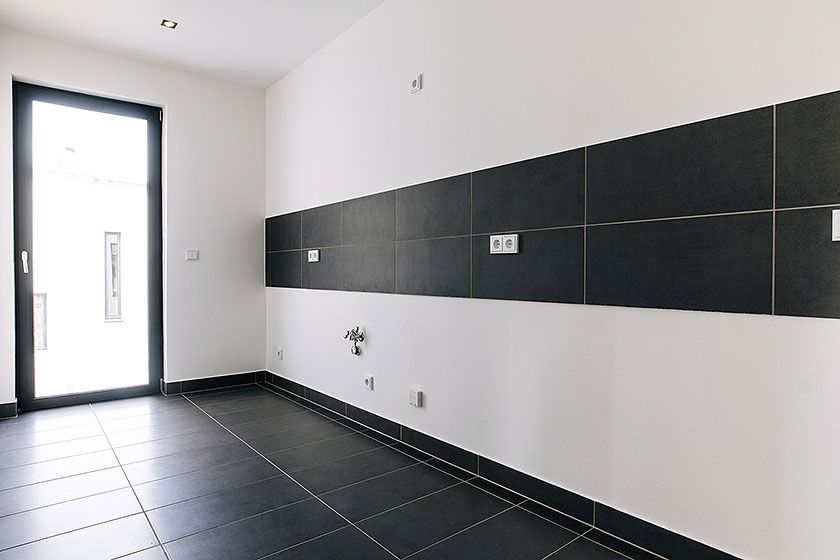 Helle, modern geflieste Küche mit großformatigen Wandfliesen und bodentiefem Fenster für viel Tageslicht