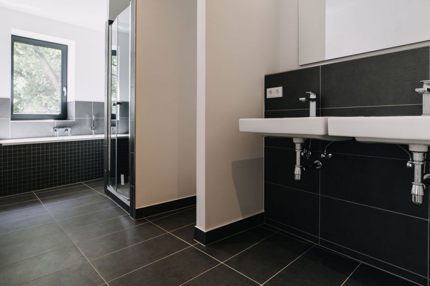 Modernes Badezimmer mit Dusche, Doppelwaschbecken, Badewanne und dunklen Fliesen