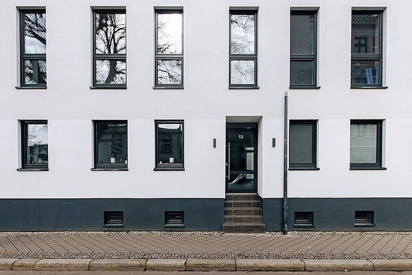 Moderne Hausfassade mit symmetrischer Fensteranordnung und zentralem Eingang in städtischer Wohngegend