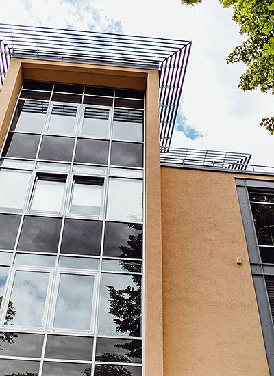 Moderne Fassade mit großen Glasfenstern und Sonnenschutzstruktur an einem mehrstöckigen Büro- oder Wohngebäude