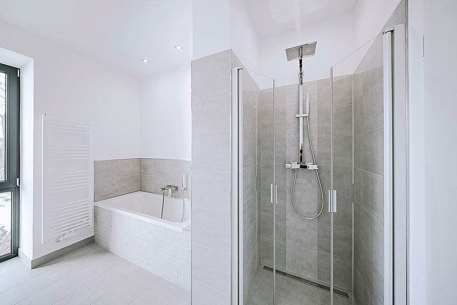 Helles Bad mit bodengleicher Dusche, Badewanne, Handtuchheizkörper und großem Fenster in moderner Fliesengestaltung