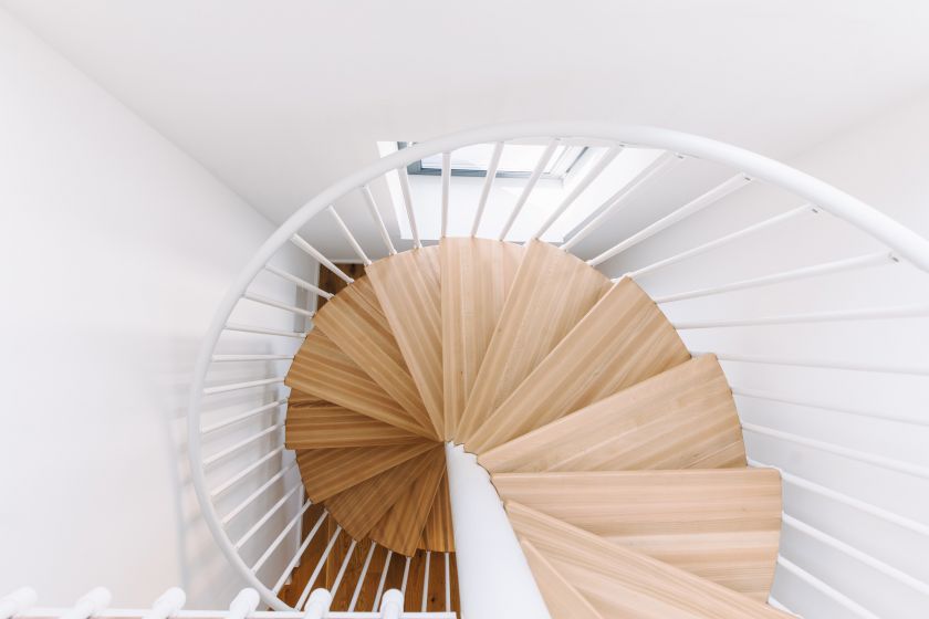 Moderne Wendeltreppe aus Holz mit weißem Geländer in heller Innenarchitektur